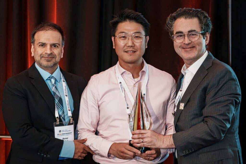 Three men holding an award trophy.